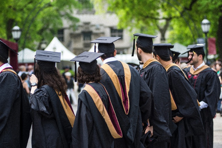 The backs of graduates wearing gowns and caps