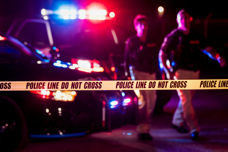 Two police officers behind crime scene tape