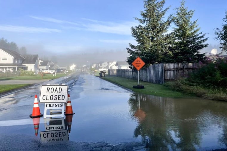 Cones and a road closed sign on a flooded residential street