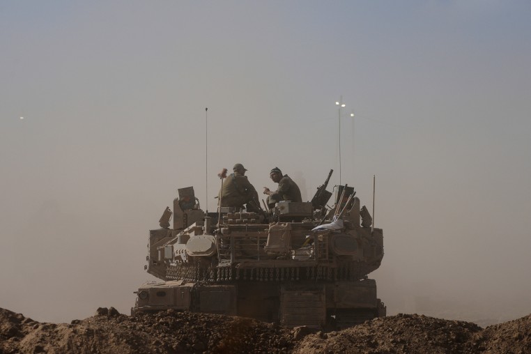 Israeli soldiers sit on top of tank parked