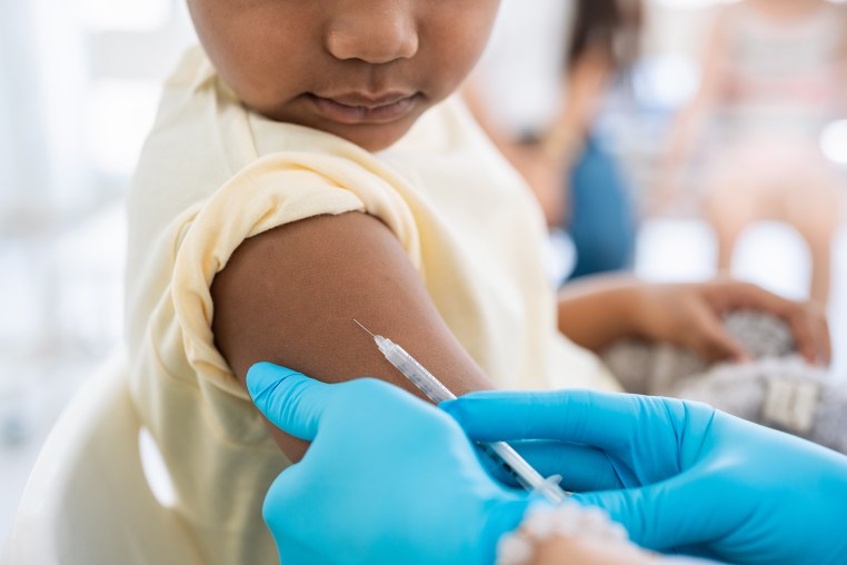 Young boy getting a shot at doctor's office and looking at needle
