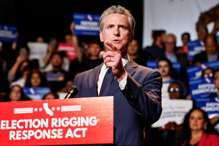 Gavin Newsom speaks at a podium with a red sign on it that reads "Election Rigging Response Act"