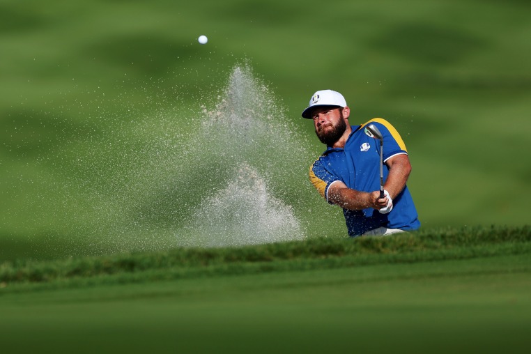 Tyrrell Hatton hits a golf ball on the golf course, sand goes flying