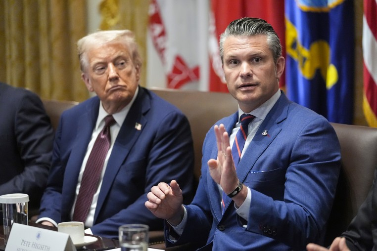 Donald Trump, left, and Pete Hegseth sit at a table as Hegseth speaks