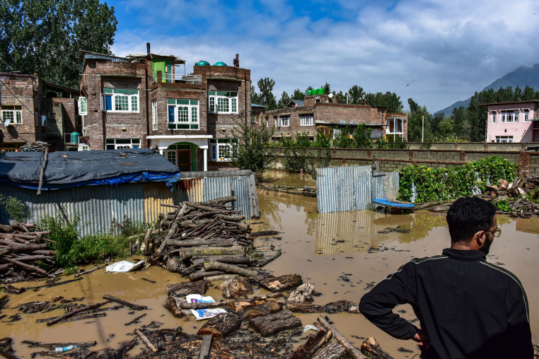 A Kashmiri man stands near his partially submerged house