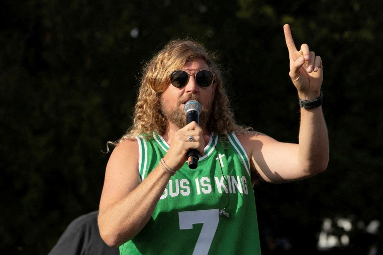 Sean Feucht raises his hand as he speaks.