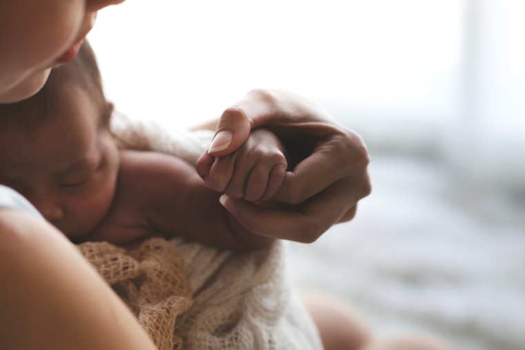 Close up Mother holding hands Asian female newborn baby  and sunlight in the morning. Cute little girl  three weeks old. Health, care, love, relationship concept.