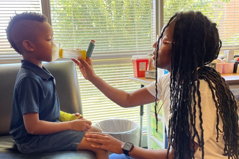 Virginia Wilson helps a young student with a breathing treatment at Premier Charter School in St. Louis.
