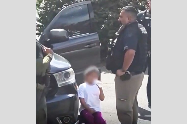 A young girl is surrounded by law enforcement agents outside a house in Leominster, Mass.