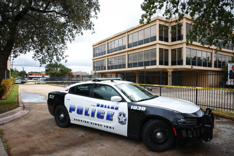 A Dallas police department car is parked in front of a building