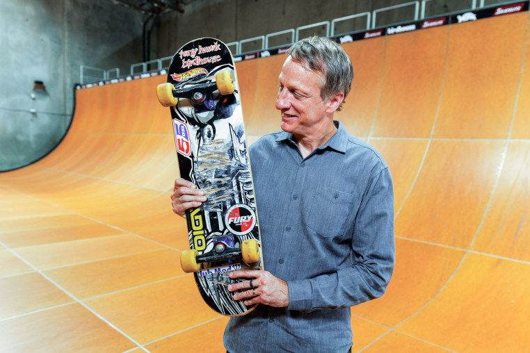 Tony Hawk holds the Birdhouse "Falcon 2" board on a skateboarding ramp.