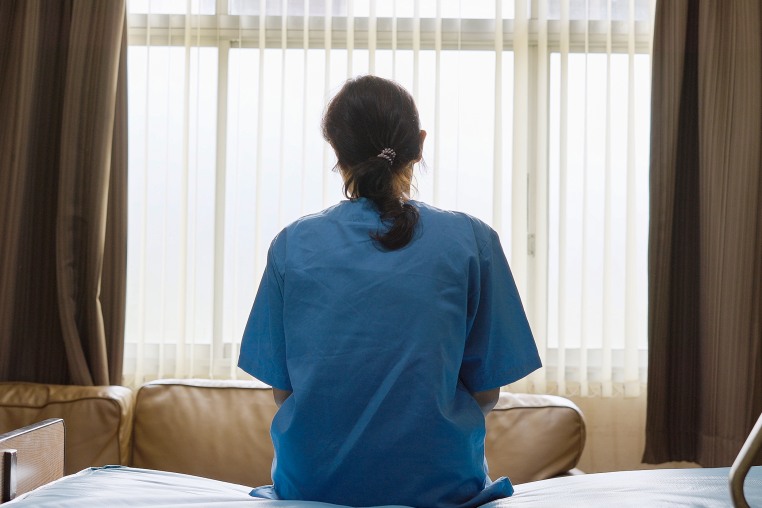 A young woman sits alone in a hospital room.
