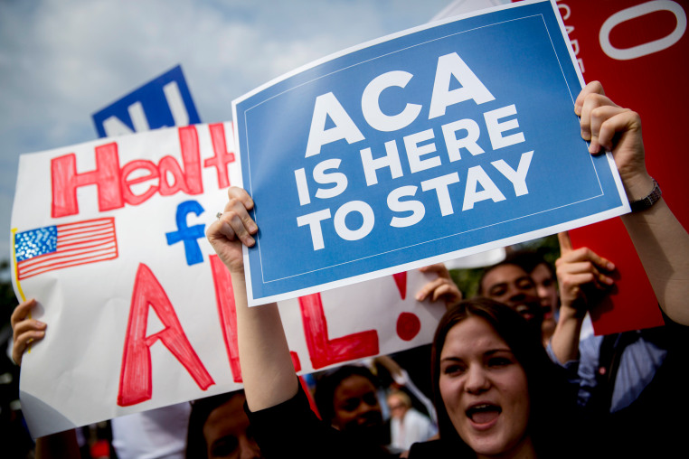 Demonstrators hold signs.