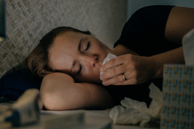 Sick woman using tissue paper at home.