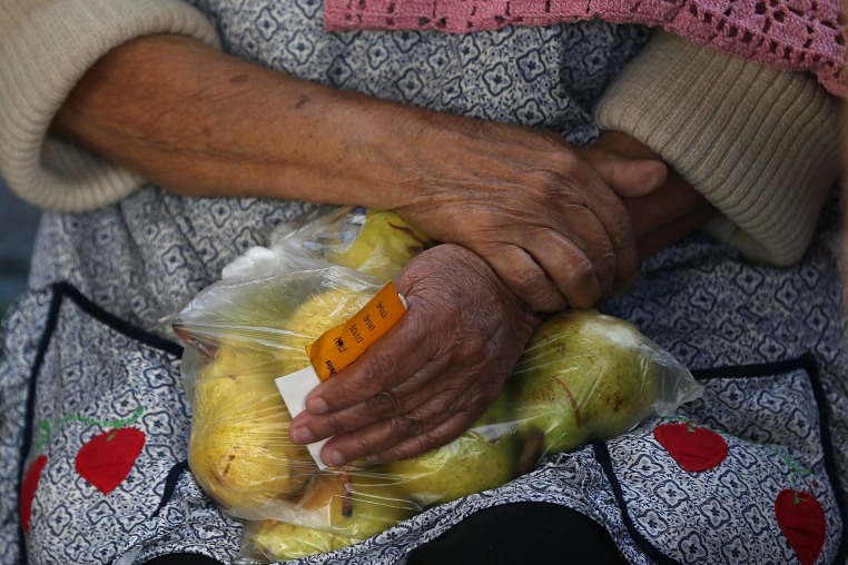 A woman holds a bag of pears as she waits in line to receive free food at the Richmond Emergency Food Bank.