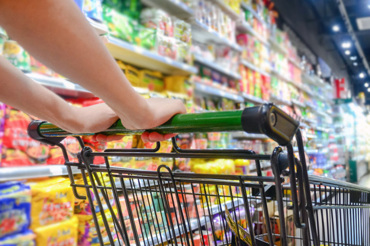 A woman pushes a shopping cart to choose products in a supermarket.