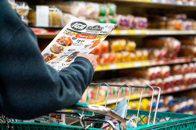 A shopper looks at a sales advertisement at a grocery store.