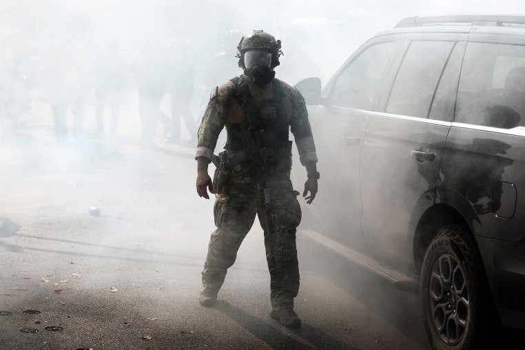 A Border Patrol agent walks through a cloud of tear gas after agents faced off against community members.