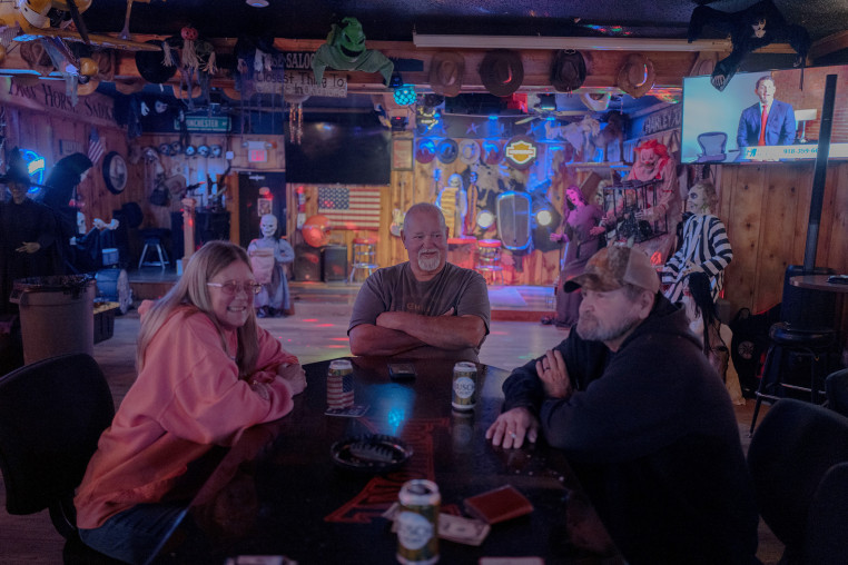 (L-R) Renae Altman, 58, Joe Brewer, 68, and Roger Valk, 72 from Oologah, Okla. sit at the Ironhorse Saloon on Tuesday. When asked about immigration they expressed hatred for immigrants and trans people.