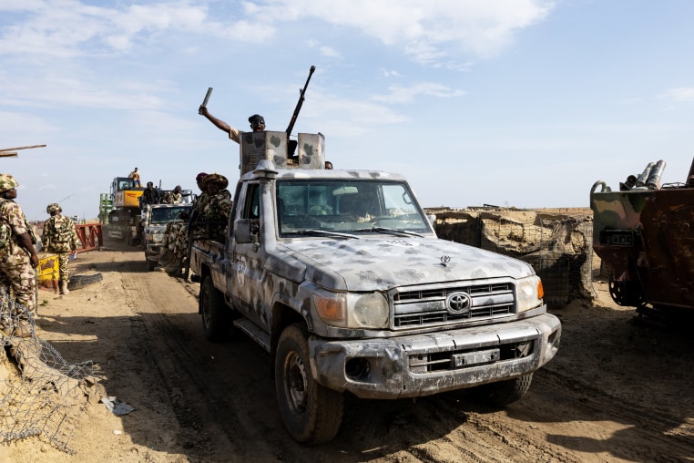 A Multinational Joint Task Force (MNJTF) military escort accompanying an excavator digging trenches passes through a checkpoint in Borno state, Nigeria.