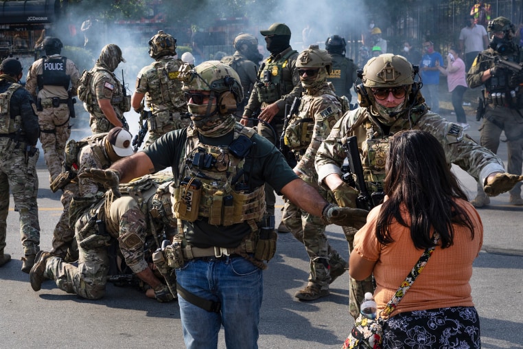 Police take two people into custody, as tear gas fills the air after it was used by federal law enforcement agents in Broadview, IL.