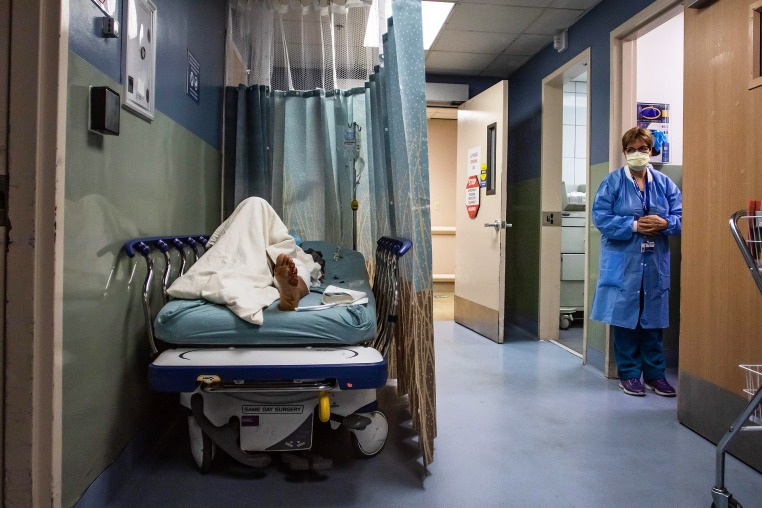 A patient rests in a corridor waiting for a room.