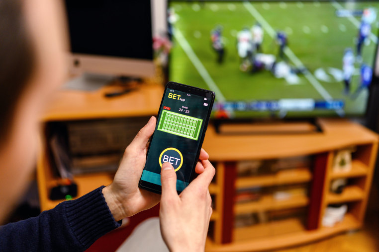 Young men using smart phone for sports betting.