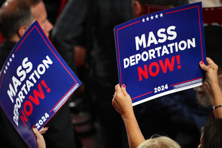 A person holds a sign that reads "Mass Deportation Now" during the third day of the Republican National Convention.