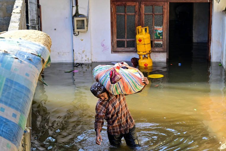 A man with his belongings wades through floodwaters outside his house in Wellampitiya on the outskirts of Colombo, Sri Lanka, on Nov. 30.