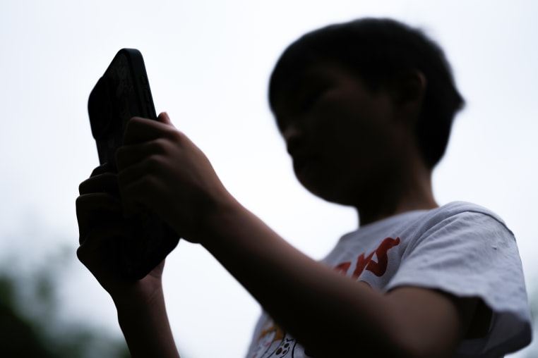 A boy uses a cellphone outside