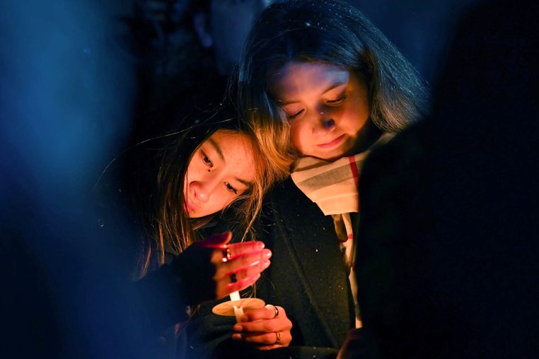 People hold candles during a vigil, Sunday, Dec. 14, 2025, in Providence, R.I.,