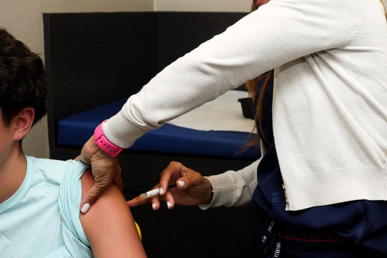 Medical Assistant gives a flu shot to a child at pediatric office.
