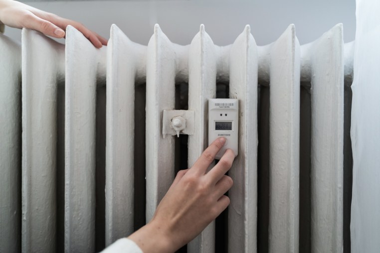 Young woman near the home radiator with temperature sensor