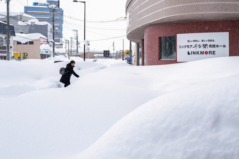 A pedestrian walks on the snow covered pavement