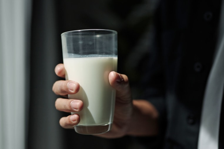 Hand holding glass of milk.