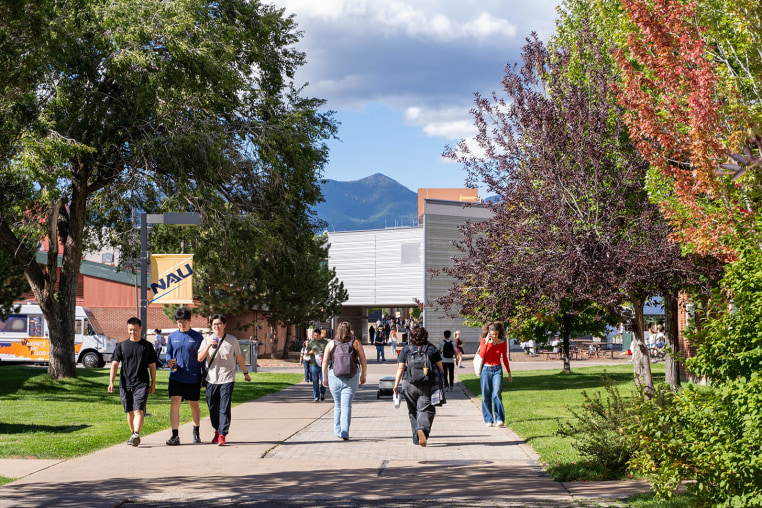 Students walking on Northern Arizona University campus with San Francisco Peaks background
