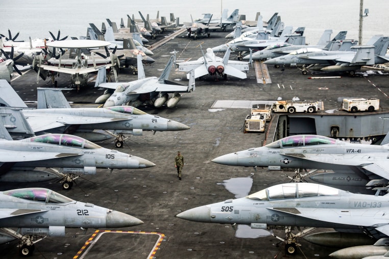A US Navy officer walks past fighter jets parked on the flight deck of the Nimitz-class aircraft carrier USS Abraham Lincoln