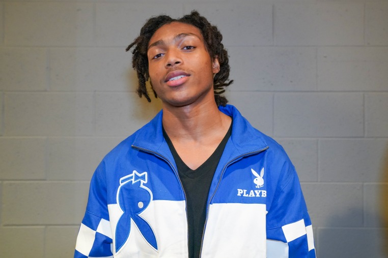 Young Slade is photographed against a white brick wall