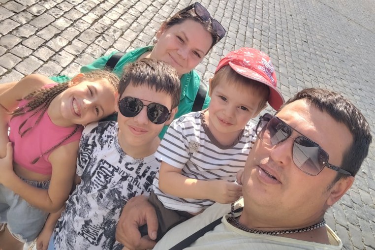Oksana, center, and Nikita, left, pose with their children for a photo
