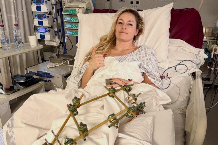 Lindsey Vonn lays on a hospital bed with a metal medical device on her leg to straighten it