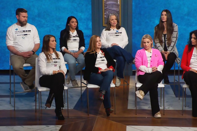Seven women and one man sit orderly on a TV studio while being interviewed.