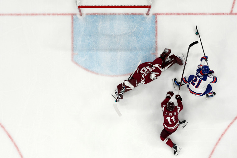 Three hockey players are seen on the ice from an elevated, bird's-eye perspective.