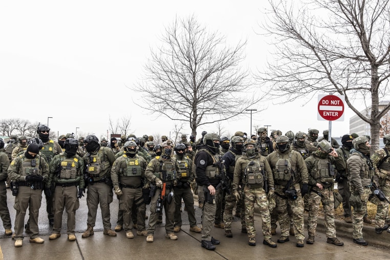 Federal Agents stand guard outside an ICE facility during a protest following the fatal shooting of Renee Good. 