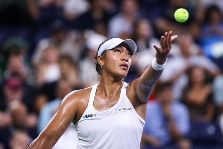 Destanee Aiava tosses up a tennis ball on the court