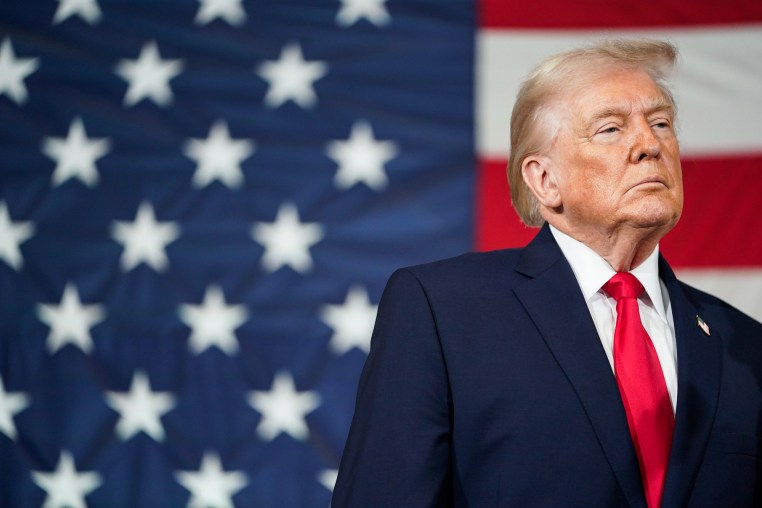 Donald Trump stands in front of an American flag backdrop
