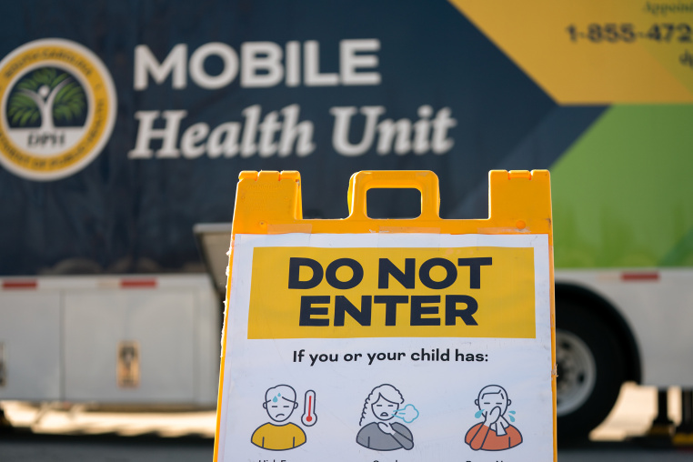 A sign reads DO NOT ENTER with graphic illustrations of people experiencing illness. 