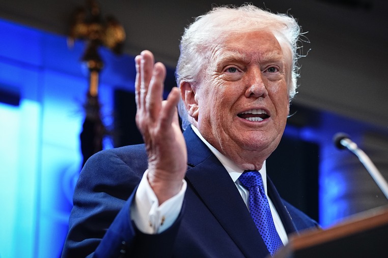 President Trump gestures with one hand while speaking at a lectern at the White House.