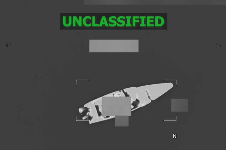 A black and white aerial view of a boat on the water, green text at the top reads "unclassified"