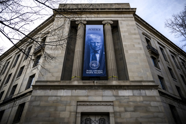 Image: A a new banner featuring an image of President Donald Trump is displayed on the facade of the U.S. Department of Justice 