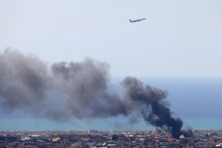 A Middle East Airlines aircraft takes off from the airport in Beirut as smoke rises from the site of an Israeli air strike that targeted an area in the southern suburbs of the Lebanese capital on March 17, 2026.